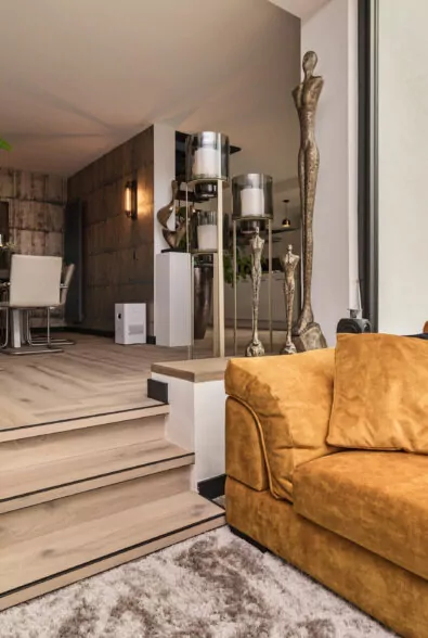 Woonwinkelinterieur met okergele fauteuil, houten vloer en decoratieve beelden