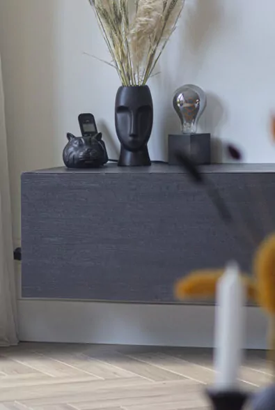 Zwart dressoir met vaas, decoratie en een tafellamp