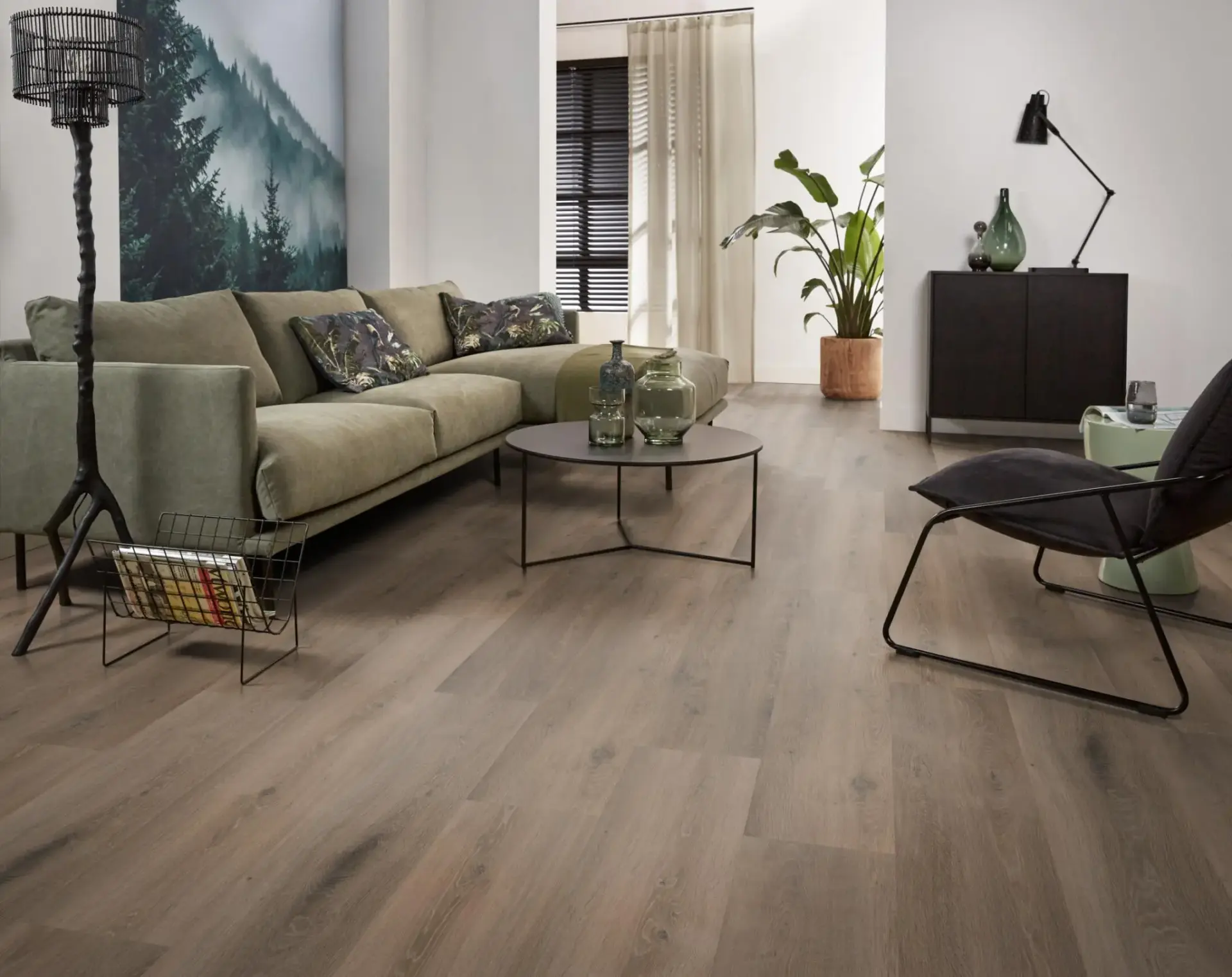 Woonkamer met brede houten vloerdelen, bank en fauteuil